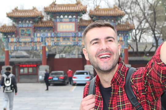 Caucasian tourist taking a selfie with traditional Asian temple