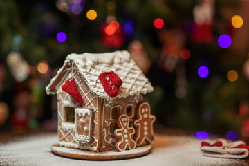 Homemade gingerbread house with candy windows on a wooden table with Christmas decorations