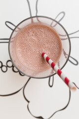 Top view of strawberry protein shake or milkshake in glass with striped straws. Top view of the drink. Healthy drinks and snacks. Nutrition concept
