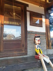 Pinocchio is sitting in a Korean-style house (Hanok)