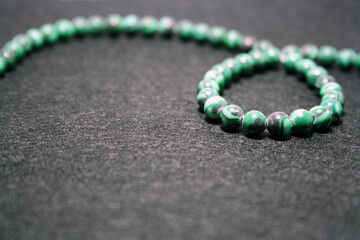 Green beads on a black felt background.