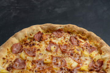 Tasty hawaiian pizza with cheese ,crispy bacon and pineapple on dark background with copy space .