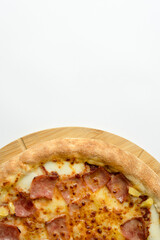 Tasty hawaiian pizza with cheese ,crispy bacon and pineapple on wooden pizza board and white background.Top view with copy space for text, restaurant food concept.