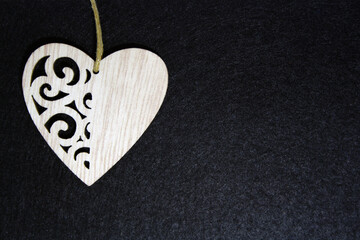 Wooden heart on a black felt background.