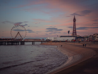Blackpool Tower and the ferris wheel of the North Pier in a wide shot at sunrise during the winter