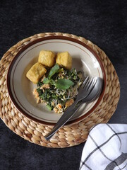 High angle view of urap sayur or boiled vegetables with spicy grated coconut and fried tofu served in plate. Indonesian traditional salad. Healthy food which can be served as one of lunch menu.