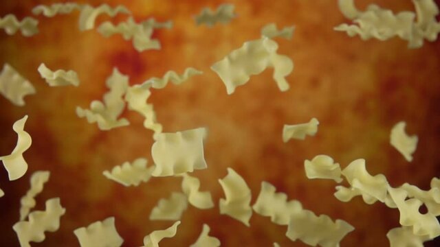 Italian Pasta mafalde corte is flying up on a yellow ochre background in slow motion