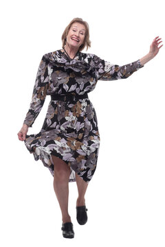 Happy senior woman wearing dress dancing with hands raised