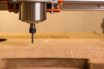 The head of the CNC machine cuts out a wooden decorative thing. The camera follows her. Splinters...