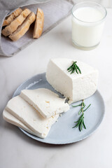 Adyghe cheese is cut into pieces on a gray plate. Soft goat cheese