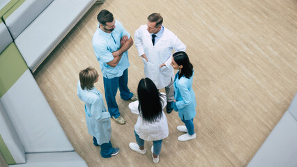 Top view full-length photo of happy successful medics team while conversation at the hospital