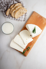 Adyghe cheese is cut into pieces on a wooden cutting Board on a light background. Soft goat cheese