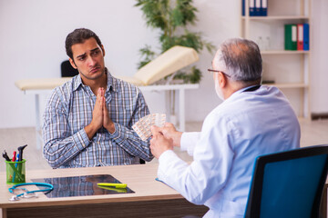 Obraz premium Young male patient visiting aged male doctor