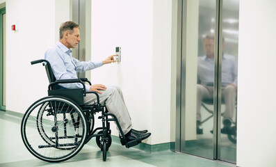 Ill senior man in a wheelchair is pushing on the button for call elevator in the hospital