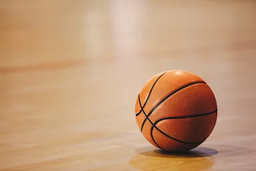 Muurstickers Orange basketball ball on wooden parquet. Close-up image of basketball ball over floor in the gym © matimix