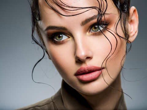 Closeup portrait of a beautiful young fashion woman with glamour makeup posing at studio.