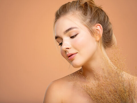 Calm Blonde girl with a bunch spring dry field flowers near the face - over colored background. Beauty face care concept.