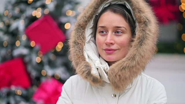 Happy woman wearing white winter coat at the christmas market with decorations smiling