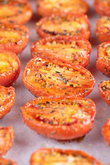 Roasted tomatoes are lined up on a baking sheet covered in spices