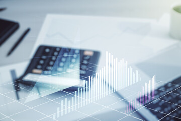 Abstract virtual financial graph hologram on calculator and laptop background, forex and investment concept. Multiexposure