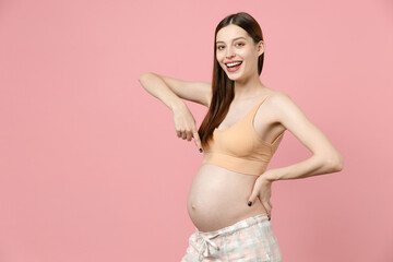 Happy young pregnant woman future mom in basic top stroking keeping hands on big belly stomach tummy with baby isolated on pastel pink background studio. Maternity family pregnancy gynecology concept.