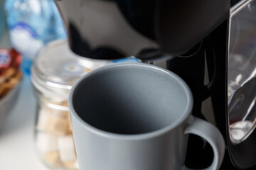 The coffee machine pours cappuccino into the cup. Coffee-make, coffee from the machine at home. Close-up of espresso making from a coffee machine