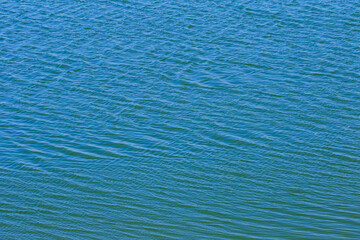 A grainy abstract image of ripples on blue water creating a pattern  
