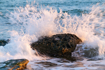 Big stone and crashing waves on sea shore