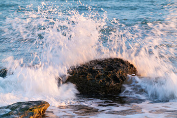 Big stone and crashing waves on sea shore