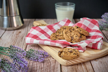 Chocolate cookies with a glass of milk and a jug of coffee on a wooden table