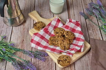 Chocolate cookies with a glass of milk and a jug of coffee on a wooden table