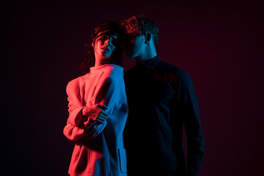 Couple standing in dark room with red and blue neon lighting. Couple in love. Sensual. 
