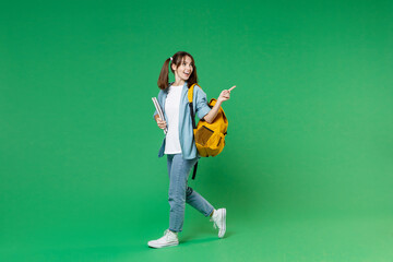 Full length side view of funny young woman student in blue shirt backpack hold notebooks pointing...
