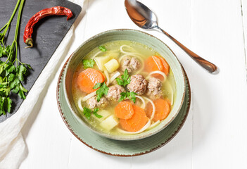 Meatball soup and ingredients on wooden table.