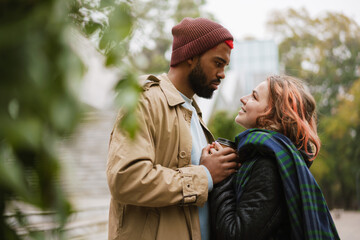 Multinational lovely couple looking at each other on city street