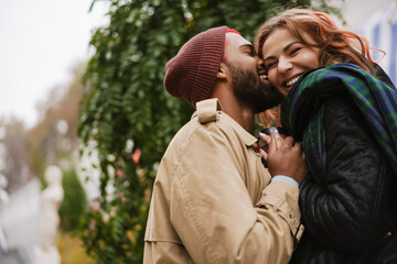 Multinational lovely couple smiling at each other on city street