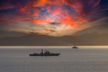 Seascape with silhouettes of warships at sunset