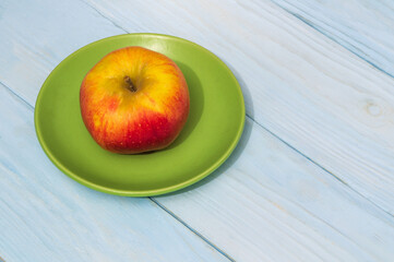 One apple on green plate. The idea of a fasting diet after the holidays