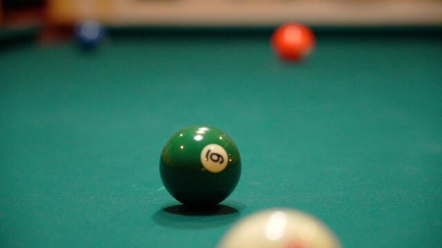 Slow Motion Billiards Cue Ball Passes Green 6 Ball and Hits Purple 4 ball with Spin and Full Contact Close Up on Pool Table with Green Felt from a Low Angle