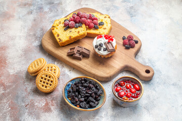 bottom view raisin cake slices on cutting board bowls with raisin and raspberry candies and biscuits on marble ground