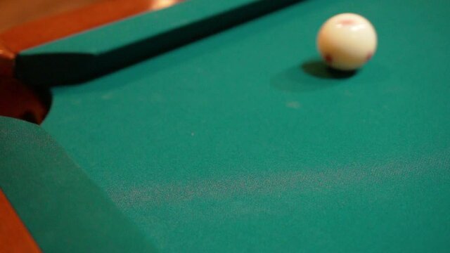 Slow Motion Billiards yellow striped 9 ball shot in corner pocket on pool table with green felt and brown pockets using the cue ball and back spin or draw Close Up with Red Spinning Dots