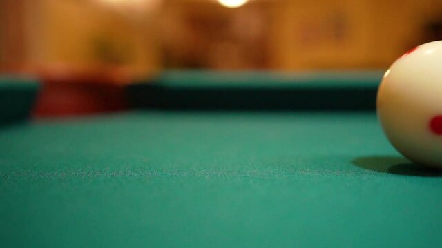 Slow Motion Billiards solid black 8 ball shot in corner pocket on pool table with green felt and brown pockets with the cue ball sliding out of frame Low Angle Close Up with Red Spinning Dots