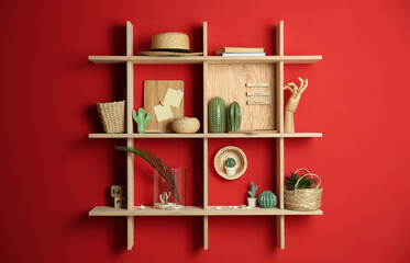 Stylish wooden shelves with decorative elements on red wall