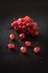 Top view closeup of red grapes isolated on a black background with water drops