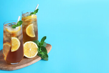 Delicious iced tea with lemon and mint on light blue background. Space for text