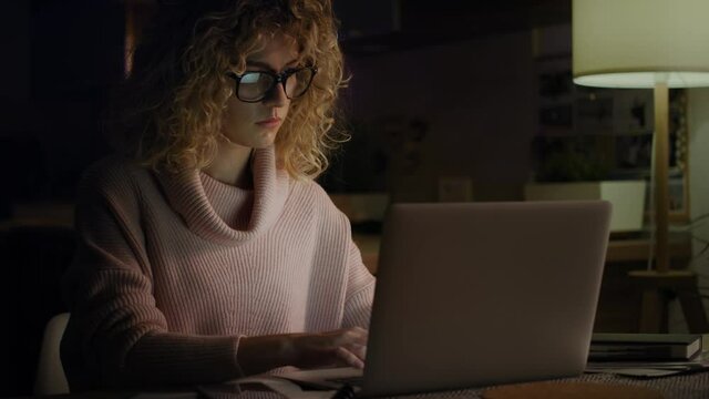 Video of tired woman working late at home. Shot with RED helium camera in 8K.