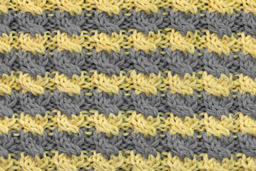 Striped gray and yellow knitted background or wool texture, horizontal stripes and cable pattern close-up view