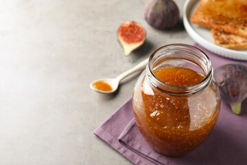 Delicious fig jam on grey table, closeup. Space for text
