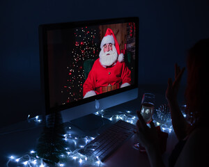 Woman talking to santa claus by video call on computer on new year's eve.