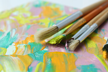 Fototapeta premium Set of different brushes on abstract colorful paint, closeup